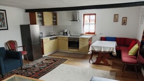 A compact living space with a kitchenette, a dining area, and seating arrangements. - Franconian half-timbered house for 5 people (Krombach)