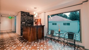 Un vestíbulo de hotel con un mostrador de recepción, un piso con diseño y un amplio ventanal que ofrece vistas al exterior.