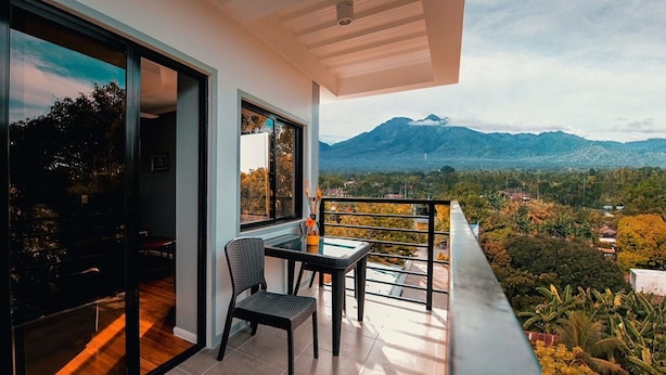 Un balcón con vistas a montañas, una silla y una mesa.