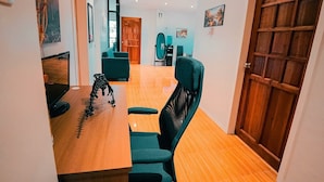 Un interior moderno con suelo de madera, un escritorio con silla, una puerta grande de madera y un pasillo que conduce a otra habitación.