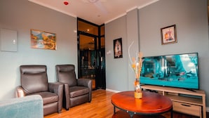 Una sala de estar moderna con dos sofás de cuero, una mesa de centro de madera y un televisor de pantalla plana sobre un mueble.
