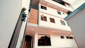 Un edificio residencial de varios pisos con techo plano, ventanas amplias y una escalera visible que conduce a los pisos superiores.