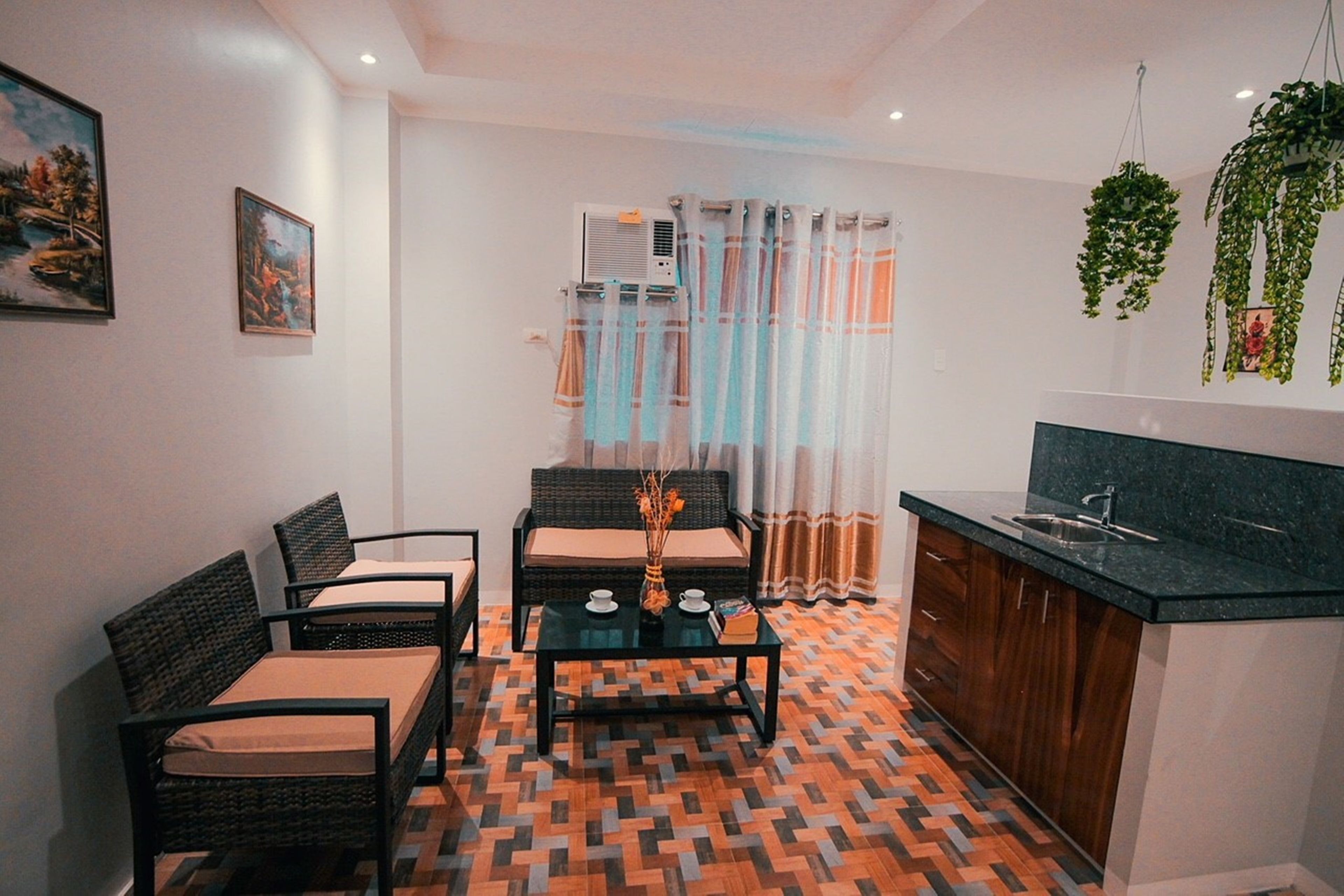A compact living space with a dining area, kitchenette, and a patterned floor.