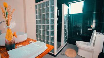 Un baño moderno con cabina de ducha de vidrio, un lavamanos blanco y un inodoro.