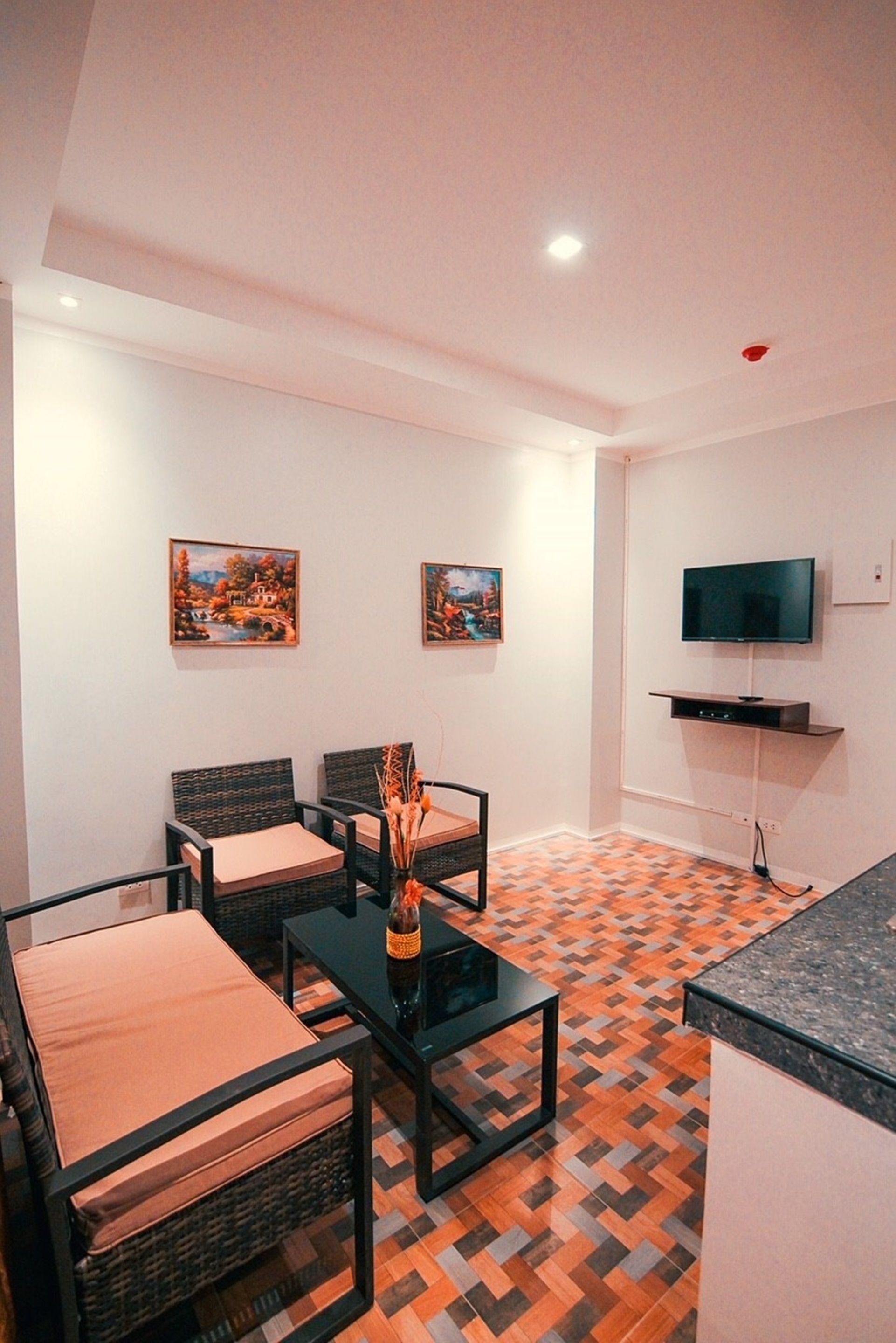 A living room with a sofa, chairs, a coffee table, and a TV mounted on the wall.