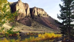 A wooden deck with a view of a river and rocky cliffs.
