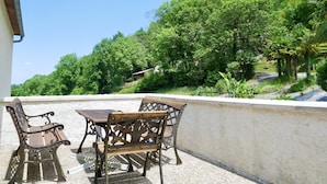 A balcony with two wooden chairs and a table, overlooking a lush green hillside. - Gite at the foot of the Pyrenees, heated pool, WIFI, games room - Fitness (Arthez-D'asson)