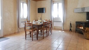A dining room with a wooden table set for six, a fireplace, and a television on the wall. - Gite at the foot of the Pyrenees, heated pool, WIFI, games room - Fitness (Arthez-D'asson)