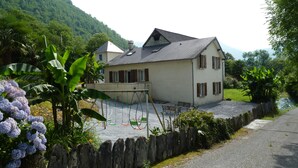 A two-story house with a stone roof and wooden shutters, surrounded by lush greenery and a gravel driveway. - Gite at the foot of the Pyrenees, heated pool, WIFI, games room - Fitness (Arthez-D'asson)