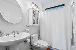 Ein Badezimmer mit weißem Waschbecken, WC und Duschvorhang.