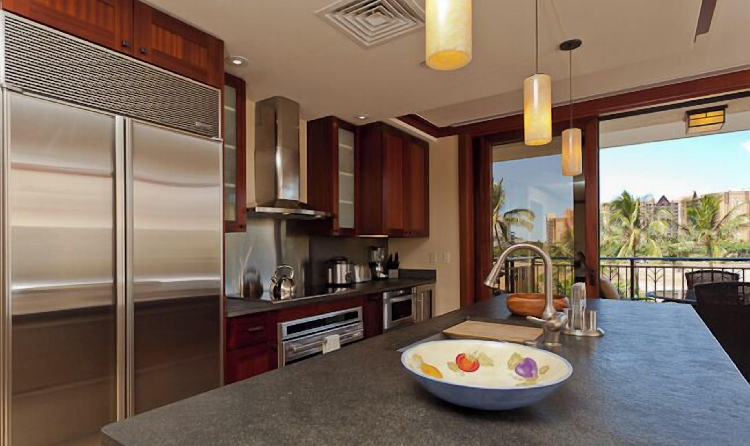 Una cocina moderna con electrodomésticos de acero inoxidable, armarios de madera y una isla grande con un bol de fruta.