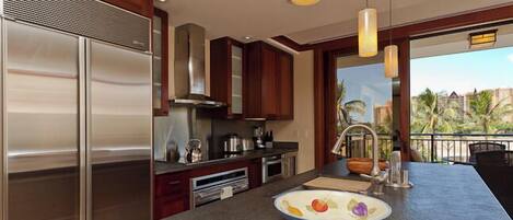 Una cocina moderna con electrodomésticos de acero inoxidable, armarios de madera y una isla grande con un bol de fruta.