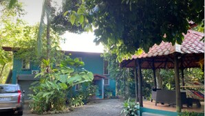 Uma entrada de cascalho leva a uma casa com fachada azul e telhado de telhas vermelhas.