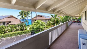 A covered balcony with a view of a residential area, including houses and palm trees.