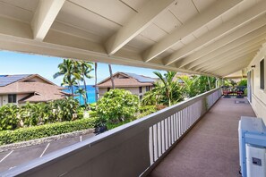 A covered balcony with a view of a residential area, including houses and palm trees. - Spacious 2BR/2BA Condo - Ocean View, Above it All, Oceanside Pool and 3 Zone A/C (Kailua-Kona)