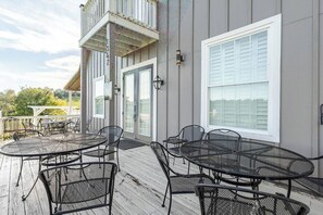 Eine überdachte Terrasse im Freien mit Metalltischen und -stühlen, einer weißen Tür und einem großen Fenster.