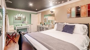 A bedroom with a large bed, bedside tables, a vanity with a mirror, and string lights on the ceiling.