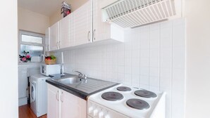 Una cocina moderna con armarios blancos, encimera negra, estufa integrada y ventana con flores.