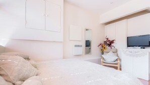 Un dormitorio con una cama, una silla, un televisor y un calentador de pared.