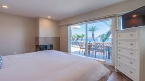 Un dormitorio con una cama grande, televisión, chimenea y vistas al patio exterior.