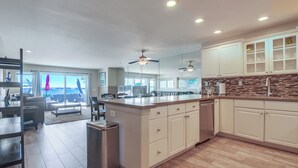 Una cocina moderna con muebles blancos, una isla grande y vistas al exterior.