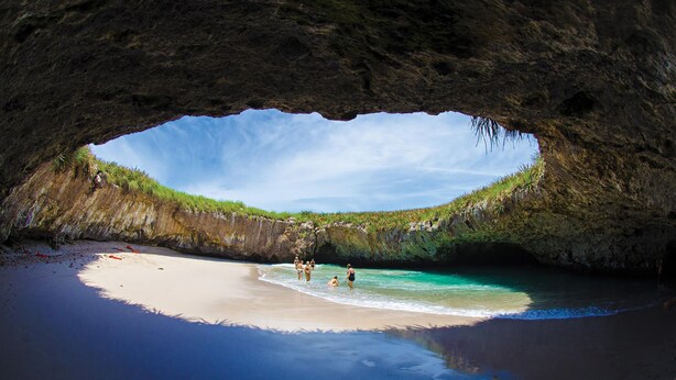A beach with clear turquoise water, a sandy shore, and a cave entrance. - Best value !! Luxury Beach Front Condo (Emiliano Zapata)