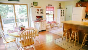 A kitchen with wooden cabinets, a dining table with chairs, and a bar area with stools.