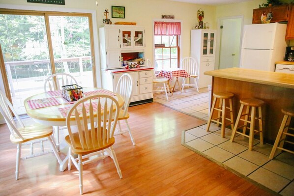 A kitchen with wooden cabinets, a dining table with chairs, and a bar area with stools. - RUSTIC FARMHOUSE with rescue donkey's, horses and chickens. (Sevierville)