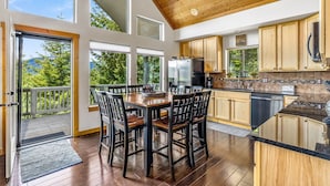 A modern kitchen with wooden cabinets, a large island, and a view of the outdoors. - 1PM In/Out + Pool Access | Scenic Mountain Cabin Built for More Family Time (Ronald)