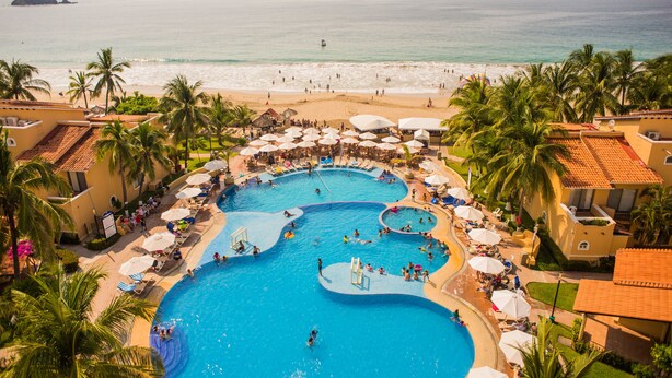Ein Resort mit großzügigem Poolbereich, Zugang zum Strand und zahlreichen Palmen.