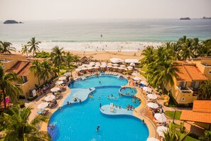 Un resort con un amplio área de piscina, acceso a la playa y palmeras.