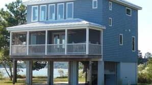 A two-story house with a covered porch and a view of the water. - Relax, Refresh, Renew..Waterfront Cottage..Near Williamsburg (Gloucester)