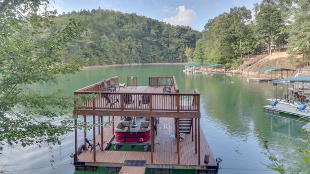 Una terraza de madera con mobiliario exterior y un barco rojo.