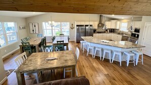 Una cocina amplia con una isla grande, piso de madera y armarios blancos.