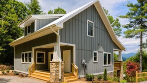 A two-story house with a prominent front porch, stone pillars, and a view of the surrounding landscape. - Newly Built Mountain Cabin With Views, Privacy And 10 Min. From Downtown! (Asheville)