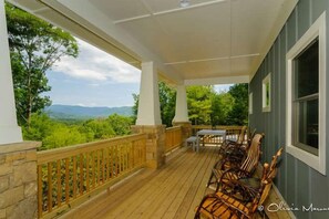 Eine überdachte Veranda mit Holzbalkonen, einem Tisch und Stühlen.