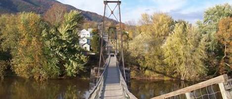 A wooden suspension bridge over a river with dense foliage on both sides.