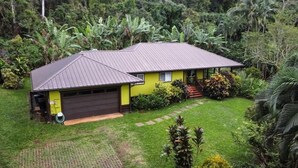 Uma casa térrea com telhado metálico inclinado, garagem e gramado bem cuidado.