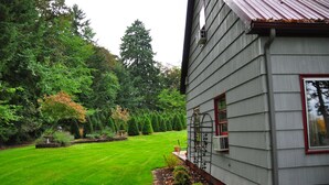 Una casa con césped cuidado y un jardín con diversas plantas y árboles.