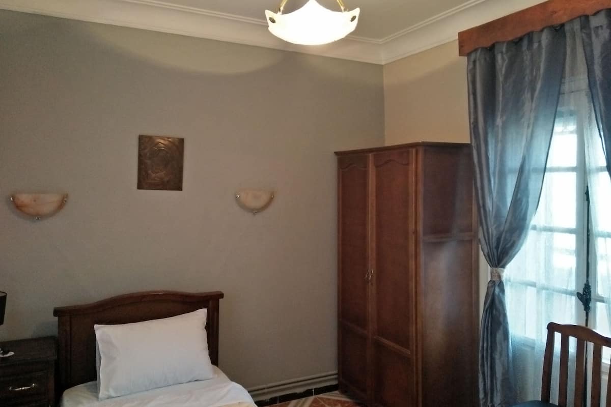 A bedroom with a bed, a wardrobe, and a nightstand.