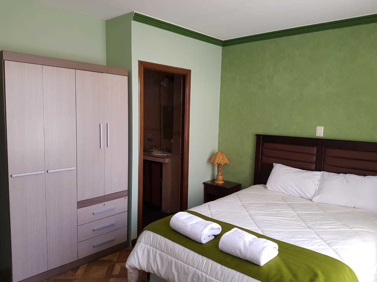 A bedroom with a bed, a wardrobe, and a bathroom door.