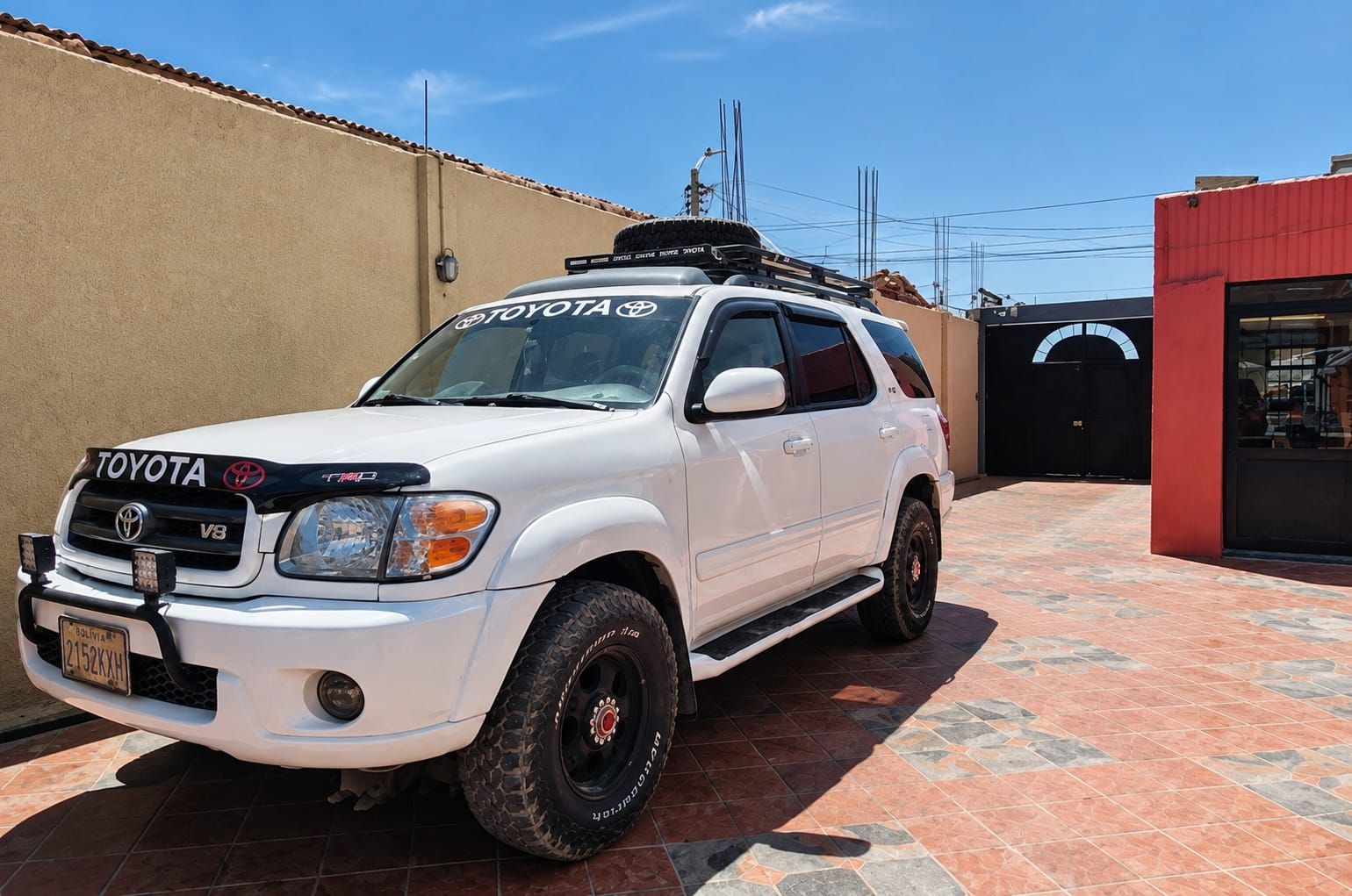 Un SUV blanco Toyota estacionado en una entrada con un patio empedrado.