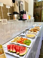 A buffet with various food items including fruits, bread, and a coffee machine.