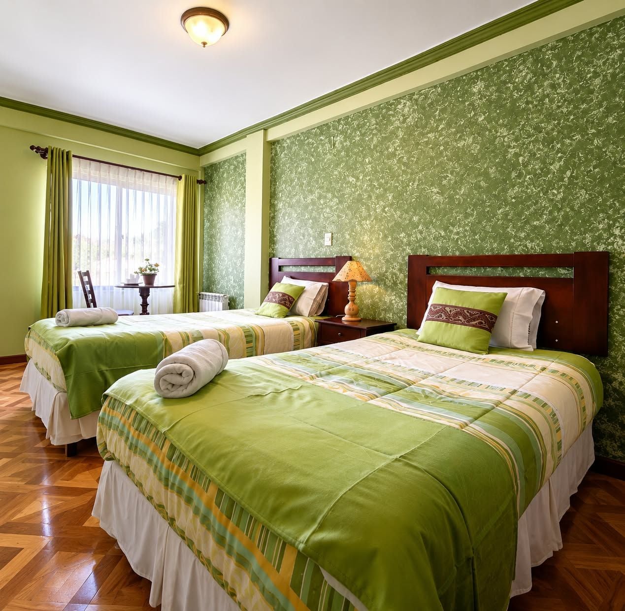 Ein Hotelzimmer mit zwei Betten, einem Tisch mit Lampe und einem fenster mit Vorhängen.