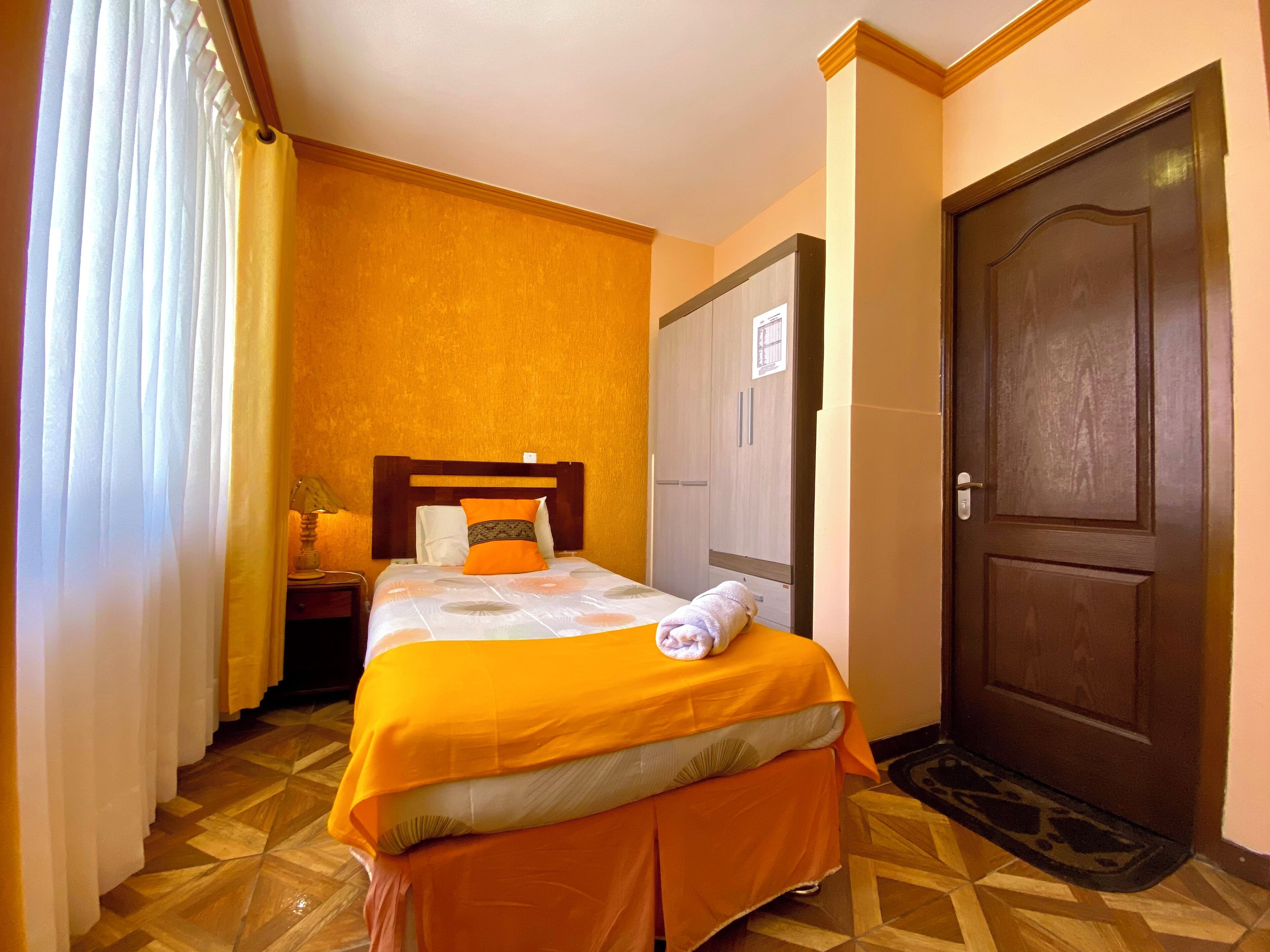 Una habitación de hotel con cama, armario, puerta y suelo estampado.