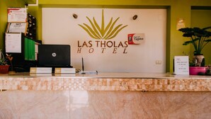 Un comptoir d’accueil d’hôtel avec une pancarte indiquant « Hôtel Las Tholas ».