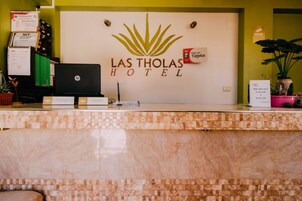 A hotel reception desk with a sign reading "Las Tholas Hotel".