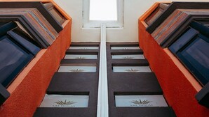 Un escalier symétrique aux murs rouges et aux marches noires, menant à une lucarne.