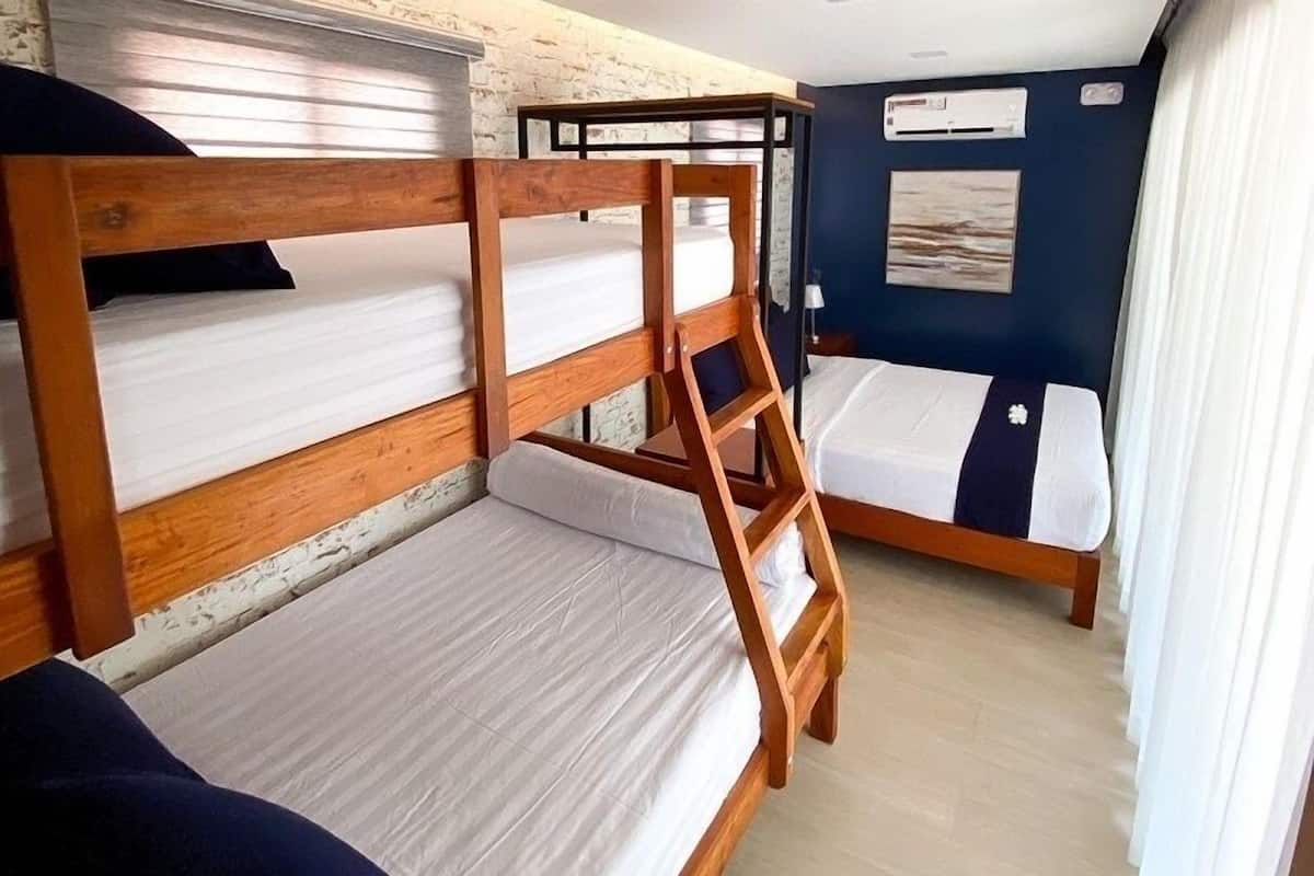 A bunk bed room with a ladder, wooden headboard, and a single bed with a pillow.