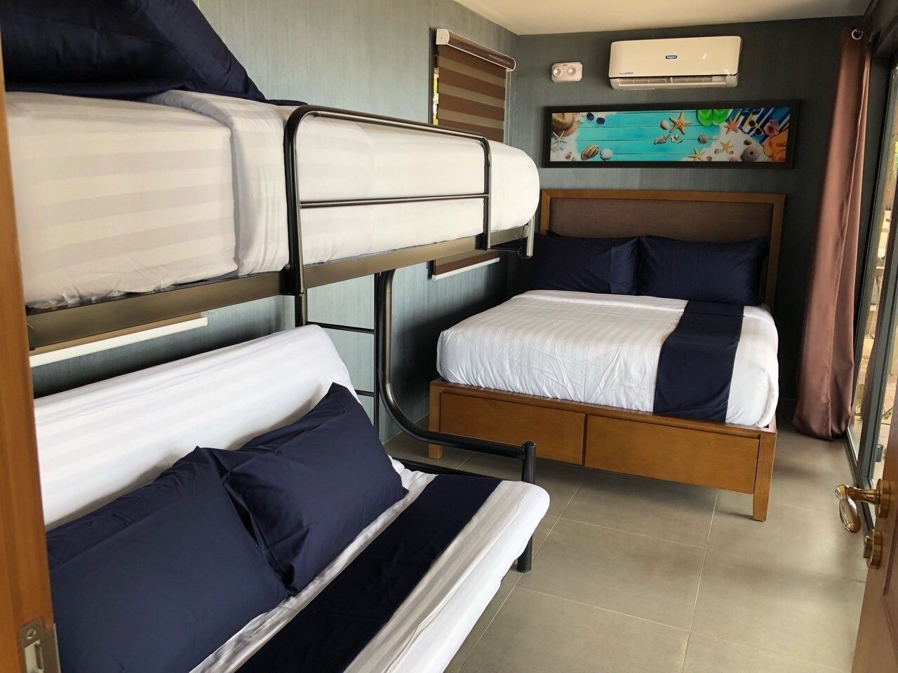 A bunk bed room with two beds, a wooden headboard, and a wall-mounted air conditioner.